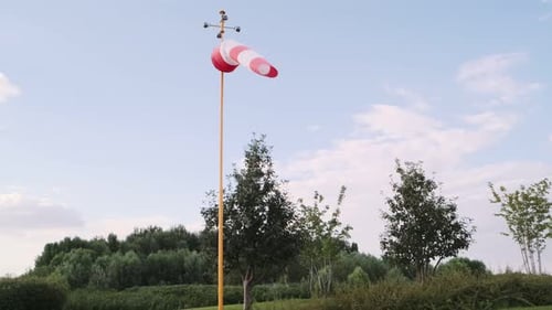 Helipad with red and white windsocks. Meadow and trees in the background