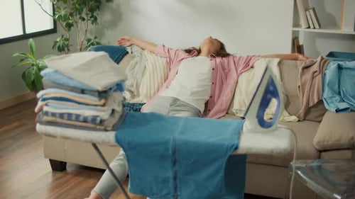Tired Young Woman Falls on the Sofa From Weakness After Ironing the Laundry