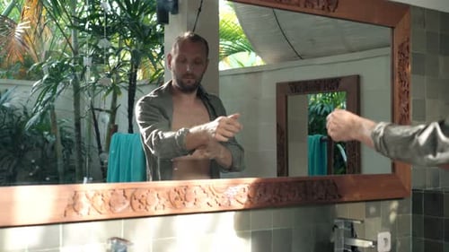 Man Correcting Shirt in Bathroom Mirror