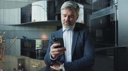 Man in Suit Using Smartphone in Modern Building