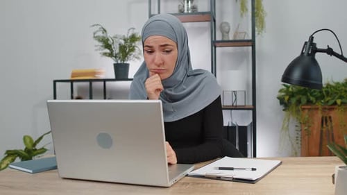 Muslim Business Woman Thinking About an Important Creative Project Work Decision on Laptop at Office