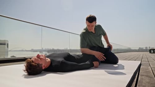 Physiotherapist Working with Female Patient on a Rooftop Mat with Expansive City Skyline in