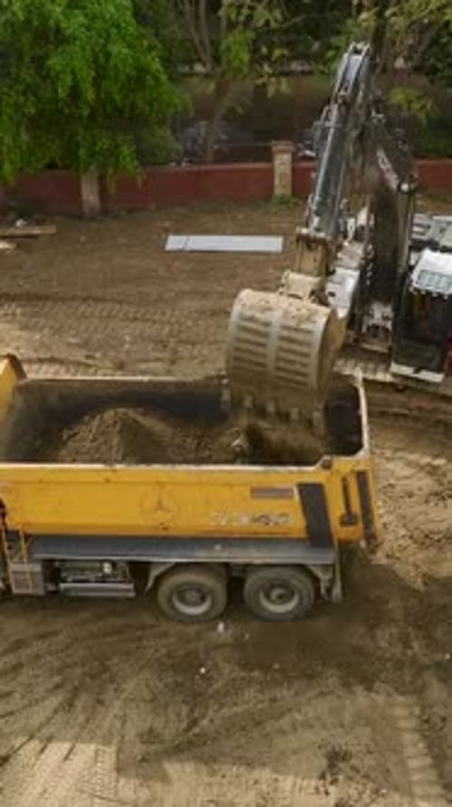 Excavator Filling Yellow Dump Truck with Dirt