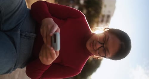 Woman Uses Mobile Phone Outside in Vertical Format