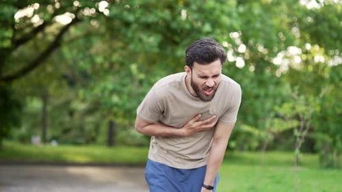 Der Sportler erlitt bei einem Lauf im Park einen Herzinfarkt oder Brustschmerzen. Er umklammert sich vor Schmerzen an die Brust