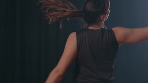 expressive dancer moves freely on dark stage under spotlight
