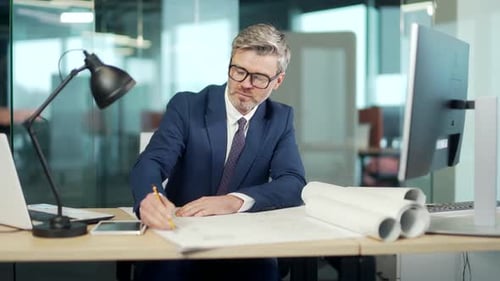 Industrial Design Engineering architect working on a Blueprints in office. Mature man real estate