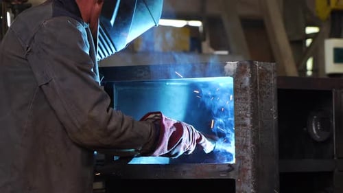 Ein Arbeiter, der eine Schutzmaske trägt, schweißt Metall in der Schwerindustrie. Metallurgie.