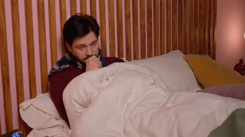 Man with scarf sitting in bed appears ill