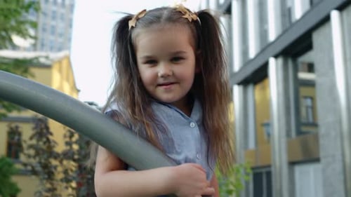 Young Girl Enjoys Playtime at City Playground During Sunny Afternoon