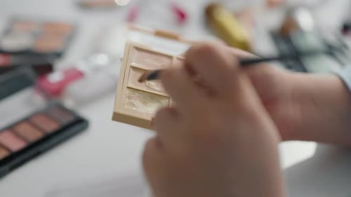 Mulher usando sombra brilhante para maquiagem Closeup de cosméticos Pincéis nas mãos Maquiagem profissional