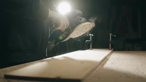 Woodworker Sands a Board with Orbital Sander
