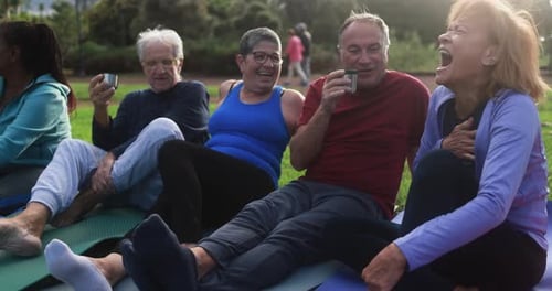 Seniors laughing and socializing on yoga mats outdoors