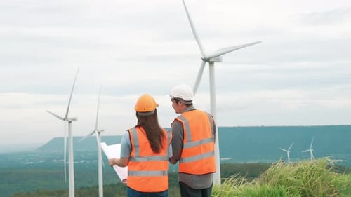 Progressive Concept of Engineers Working in the Wind Farm Atop of the Mountain