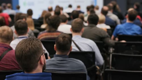 Startup team listens intently to marketing presentation in crowded conference hall