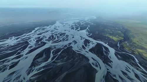 High angle panning shot showing a braided river flowing across a volcanic landscape, Iceland