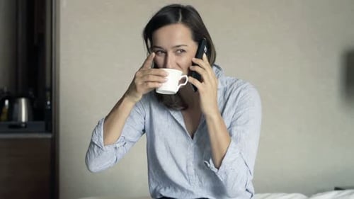 Young Businesswoman Talking on Cellphone and Eating Breakfast in Hotel Adult