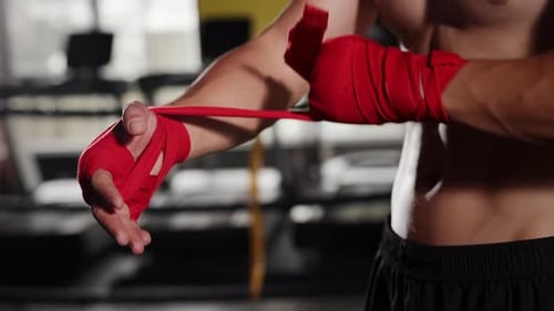 Man wrapping hands with red boxing wraps