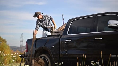 Man Tying Wood on Truck in Rural Setting