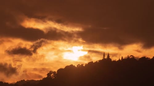 Orange Sun Rising Behind Tree Covered Hill