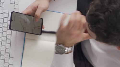 Vertikales Video eines Geschäftsmannes, der sich gezeichnete Architekturprojekte auf seinem Handy ansieht.