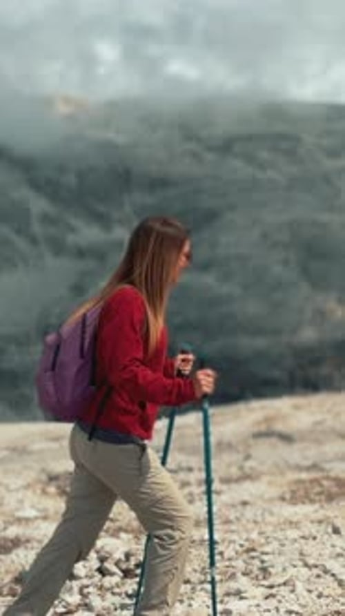 Woman Hiking in Mountains with Trekking Poles