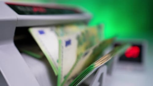 Green one hundred euro banknotes rotate in cash counting device.
