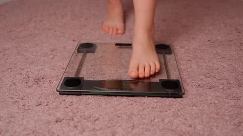 Girl stand on the scales in living room. Horizontal video young female person measuring body mass