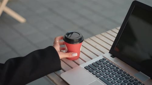 Closeup of Laptop with Tea Cup and Typing Fingers Reflection on Screen