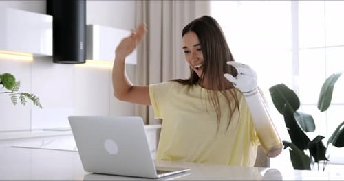 Woman with Prosthetic Arm Using Laptop at Home