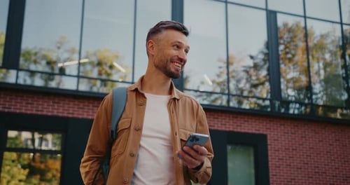 Goodlooking Caucasian Man Looking Around While Walking Down Square with Beautiful Modern Building