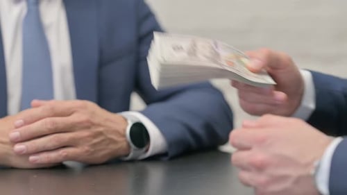 Close up of Businessman Giving Money and Shaking Hand with Investor