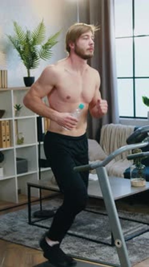 Man Running on Treadmill with Water Bottle Indoors