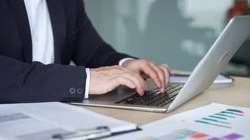 Close up of male hands typing on laptop keyboard in modern office. Asian businessman works