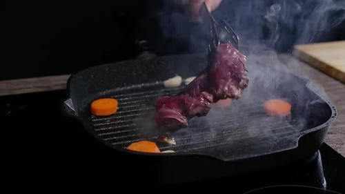 The Cook Carefully Turns a Juicy and Appetizing Beef Steak in the Frying Pan The Oil Splashes
