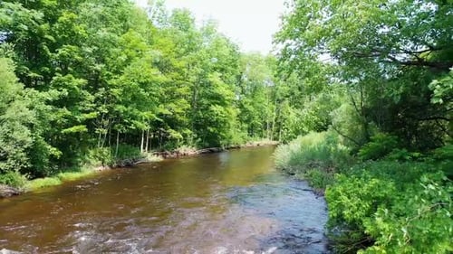 Drone effectuant un vol lent vers l'arrière au-dessus d'une rivière basse et polluée