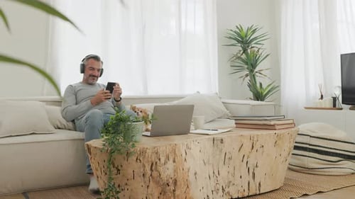 Bearded mature adult man listening to music with headphones