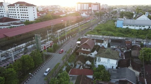 Aerial view of passenger train crossing rail bridge in near Tugu Station.