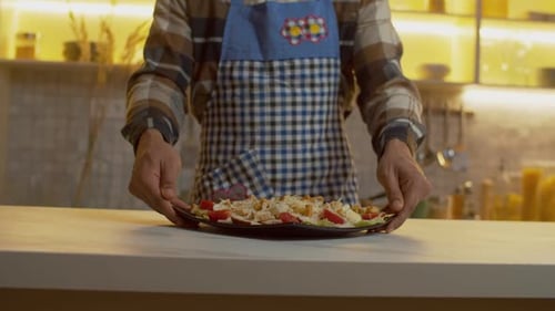 Nahaufnahme schwarzer männlicher Hände, die lecker zubereiteten Salat auf dem Tisch servieren