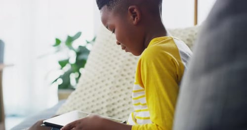 Young Boy Uses Tablet on Gray Couch