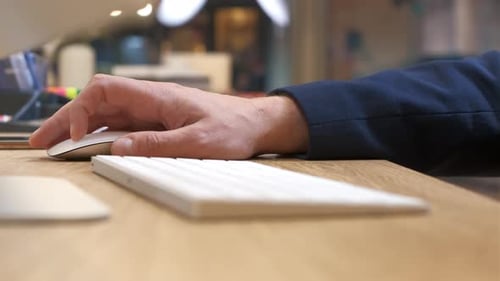 Men's hands type on a white keyboard, then scroll and click the mouse, close-up
