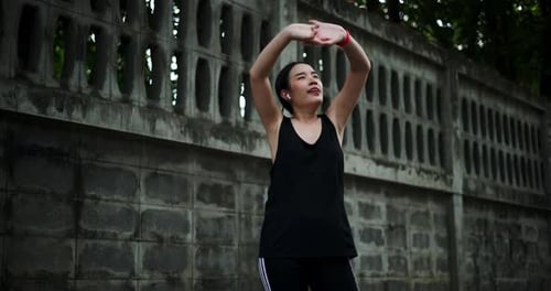 Young Woman Stretching Arms Outdoors in Urban Setting