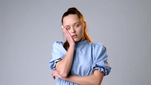 Annoyed and Tired Young Woman on Gray Background in Studio