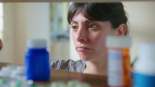 Woman Inspecting Medication Bottles in Home Setting