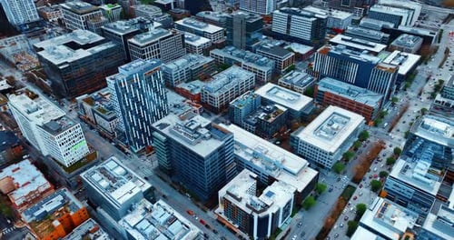 Drone flying over the roof tops in the modern American city. Scenery of Seattle, Washington at dusk.