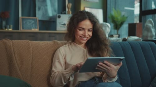 Smiling Woman Using Tablet on Sofa Indoors