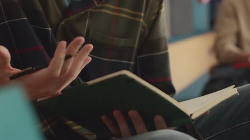 Hände eines männlichen Studenten, der während der Diskussion in ein Notizbuch schreibt