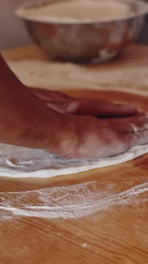 Baker kneading dough in flour on table. Hands of professional bakery chef on dough.