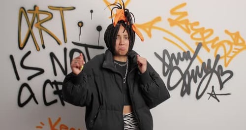 Confident Woman Dancing in front of Graffiti Wall