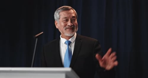 Man Giving Speech on Stage at Podium